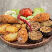 Fried chicken legs with potato and eggplant on wooden board. High quality photo