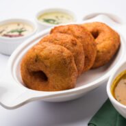 Sambar vada or Medu Vada, a popular South Indian food served with Green, Red and coconut chutney over moody background. Selective focus