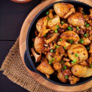 Baked potatoes with garlic, herbs and fried chanterelles in a cast iron skillet. Top view