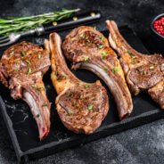 Barbecue fried lamb meat chops on a marble board. Black background. Top view.